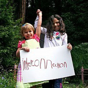 students holding raised hands wwhile holding a sign that reads “interconnection” in child’s handwriting